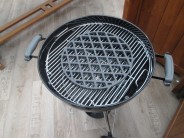 Volně položená litinová mřížka Sear Grate v grilu o průměru 47 cm.